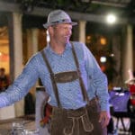 A man wearing traditional German attire shakes his friend's hand.