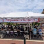 A group of poeple sit in Burgermeister's Biergarten tent.