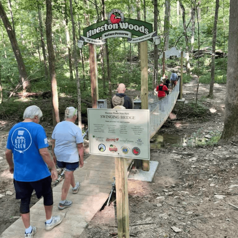 A group of people crosses the swinging bridge at Hueston Woods State Park
