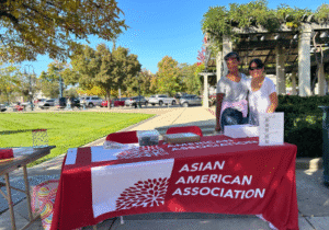 two people standing on the side of a booth that reads Asian American Association