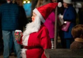 Little boy dressed as Santa holding a holiday cup