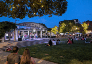 People sitting on the Oxford Memorial Park lawn in front of the pavilion at twilight